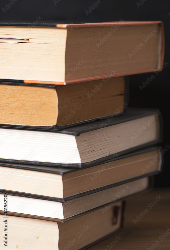 Close-up of used books stacked on black background. Vertical shoot. Close-up of used books stacked on black background. Vertical shoot.