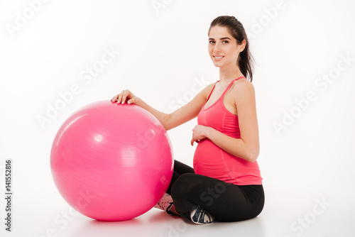 Young beautiful pregnant woman doing exercises with fitball