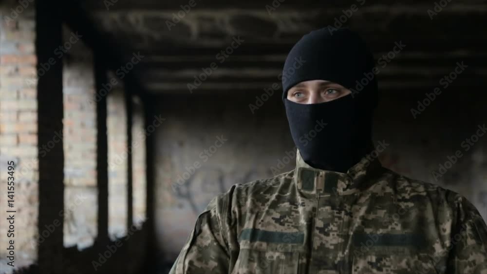 A man in camouflage and a black mask on an old abandoned building A man in camouflage and a black mask on an old abandoned building