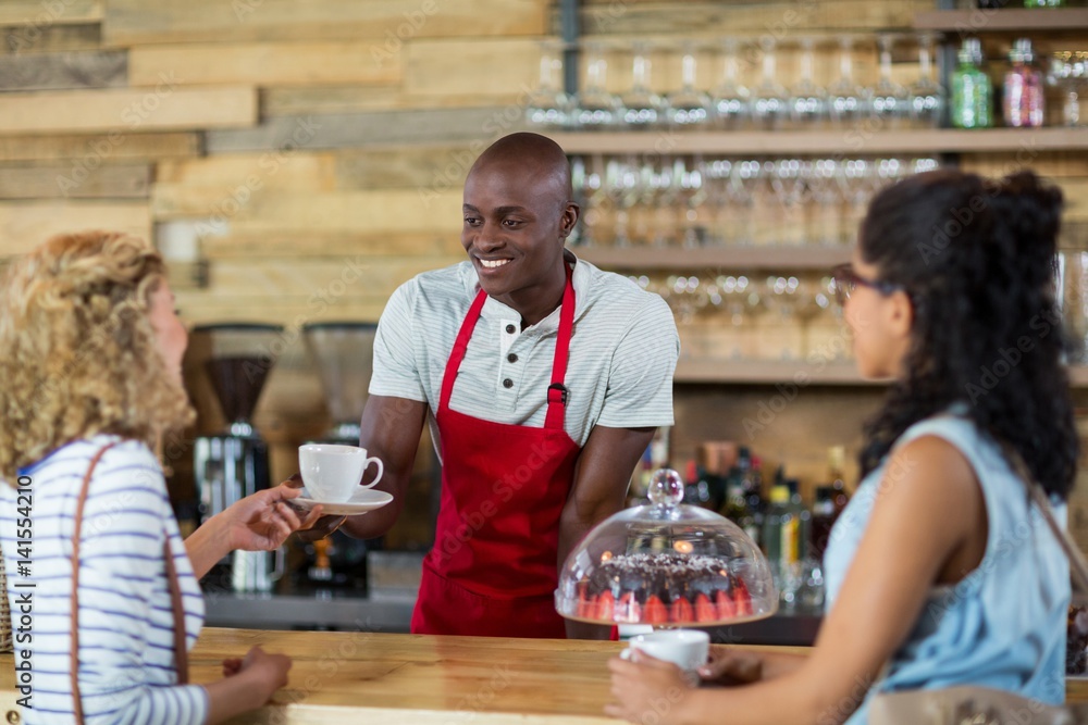 Waiter serving coffee to female customer