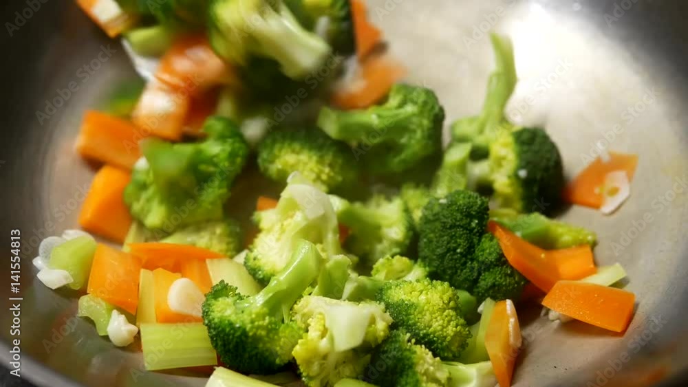 Close up of a woman cooking vegetables in frying pan Close up of a woman cooking vegetables in frying pan