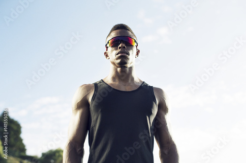 Sportsman wearing sunglasses and black tank top against sky photo