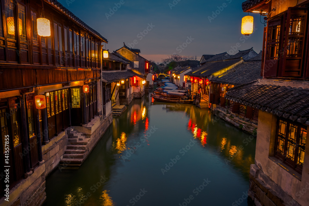 SHANGHAI, CHINA: Beautiful evening light creates magic mood inside Zhouzhuang water town, ancient city district with channels and old buildings, charming popular tourist area