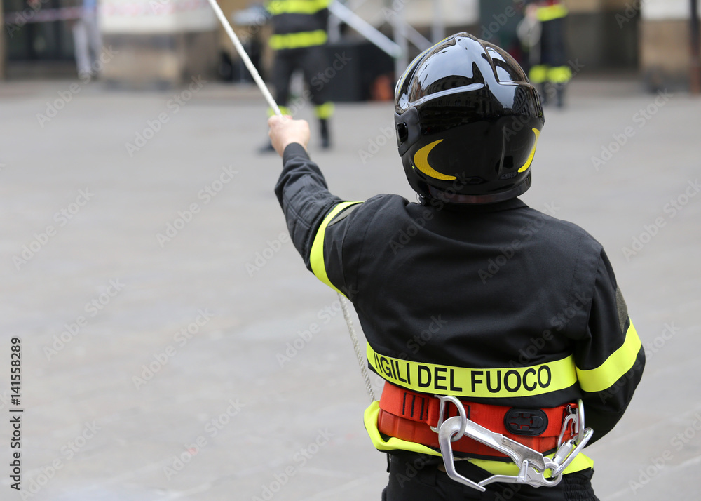 Fototapeta premium Italian firefighter with protective helmet and a rope and the wo