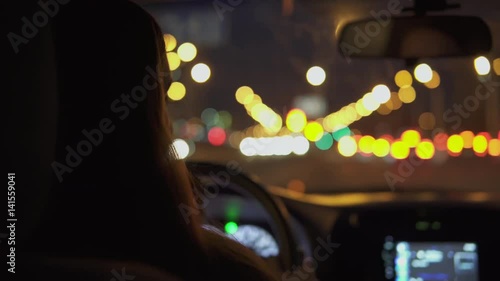 A young woman is driving a car in the night city