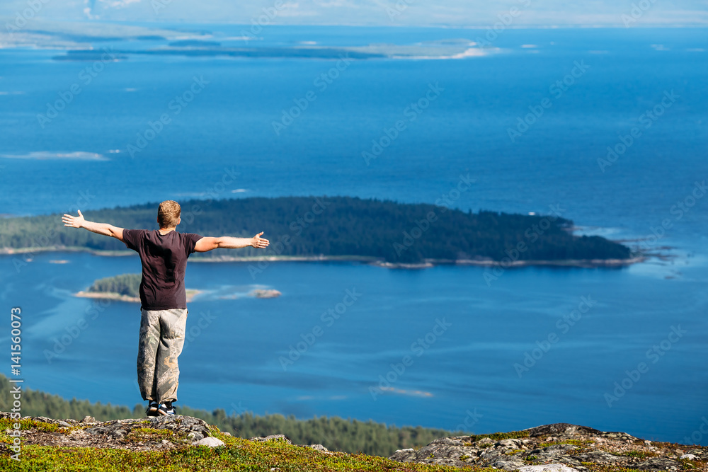 Male tourist man sitting jumping on a mountain on a white sea background. Kandalaksha, Murmansk region, the Kola Peninsula, Russia. Male tourist man sitting jumping on a mountain on a white sea background. Kandalaksha, Murmansk region, the Kola Peninsula, Russia.