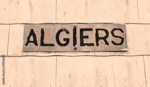 Weathered sign for the Algiers neighborhood of New Orleans in sepia