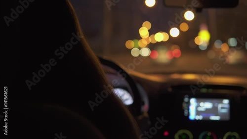 A young woman is driving a car in the night city