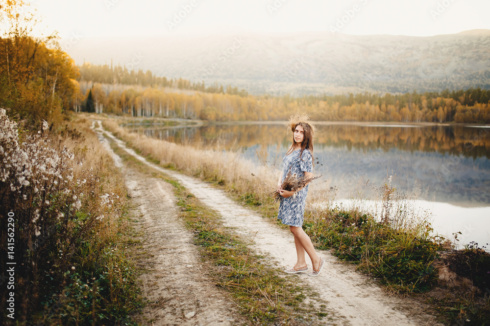 Girl on a background of forest and river, sunset, summer and early autumn.