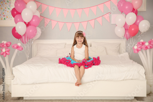 Cute girl sitting on bed in...