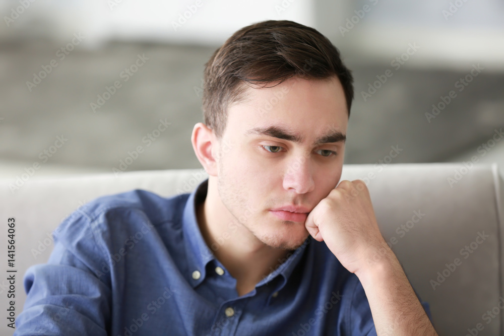 Handsome depressed man on couch at home Handsome depressed man on couch at home