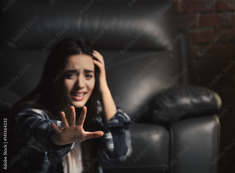 Depressed woman sitting near leather armchair indoors Depressed woman sitting near leather armchair indoors