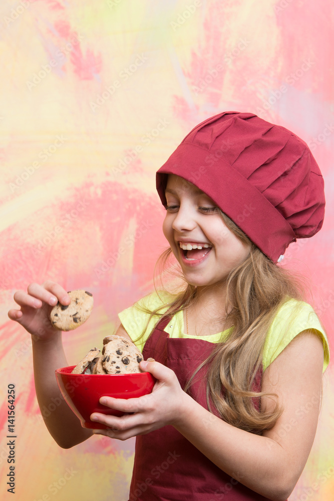 small happy girl chef in hat, apron with cookies bowl small happy girl chef in hat, apron with cookies bowl