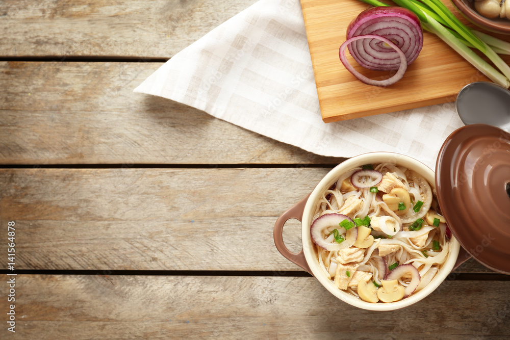 Chicken noodle soup in pot on wooden table Chicken noodle soup in pot on wooden table