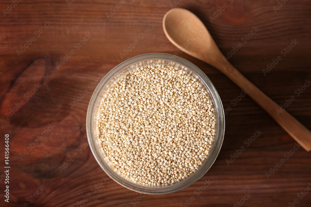 Glass jar with quinoa seeds on wooden table Glass jar with quinoa seeds on wooden table
