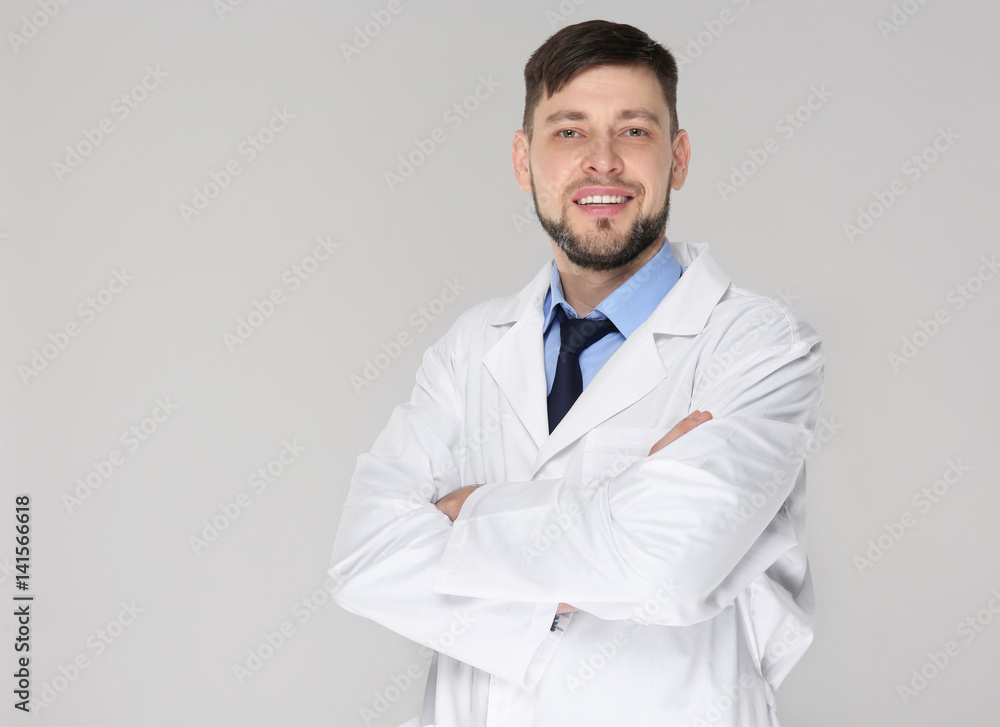 Young handsome pharmacist with crossed arms on grey background Young handsome pharmacist with crossed arms on grey background