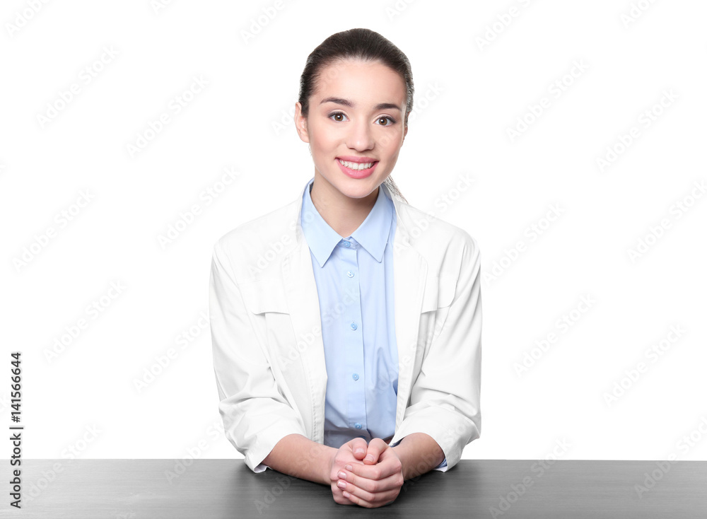 Young woman pharmacist standing at table on white background Young woman pharmacist standing at table on white background