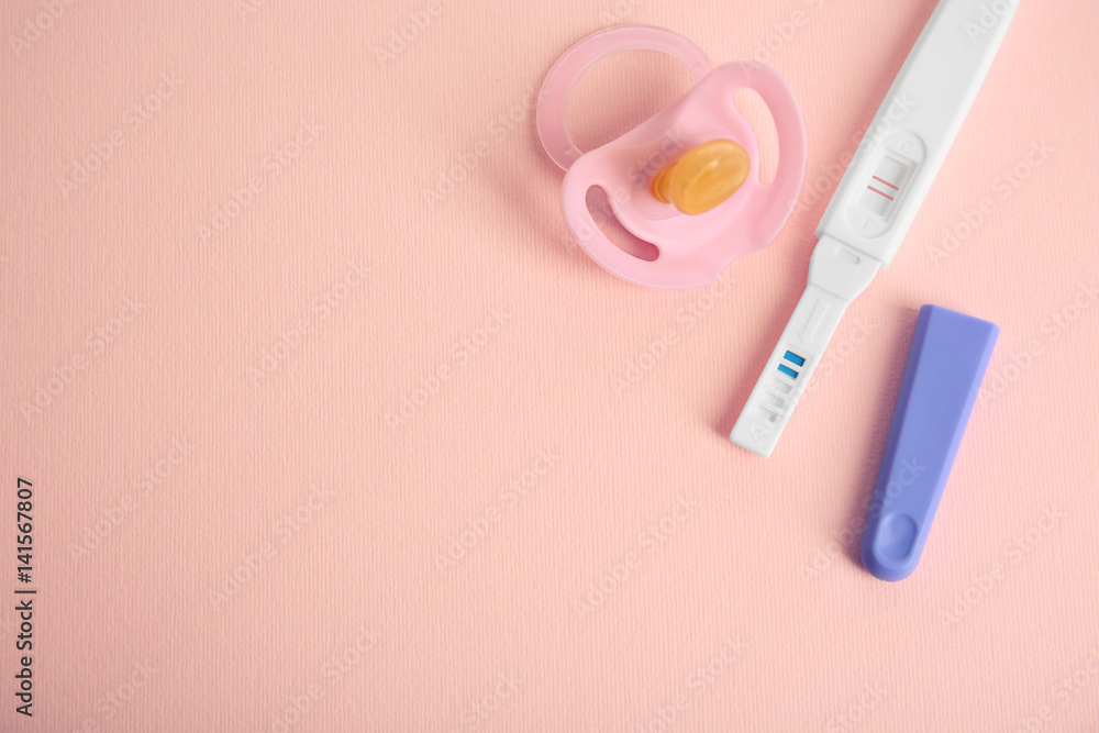 Pregnancy test and baby pacifier on pink background Pregnancy test and baby pacifier on pink background