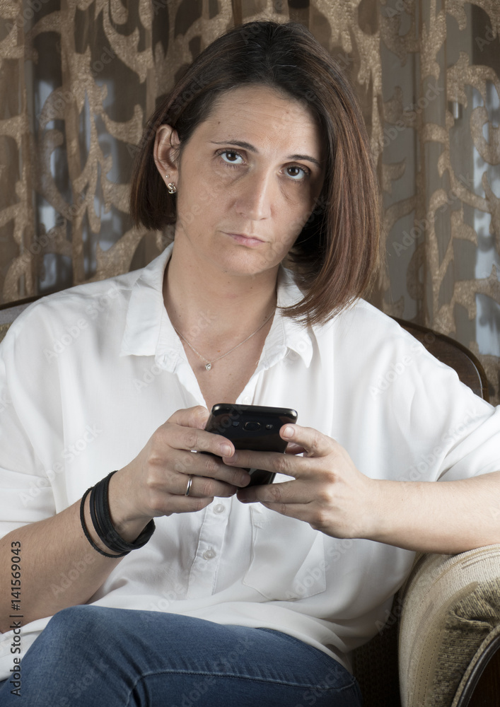 Fototapeta premium Young woman with smartphone in living room