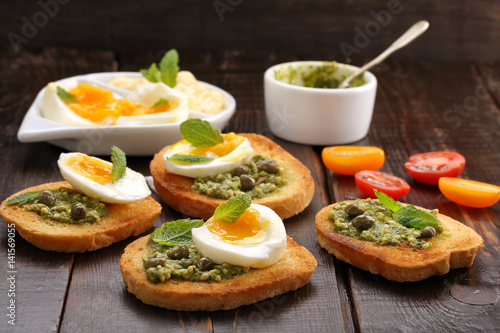 Fresh sandwich with pesto and egg on wooden background