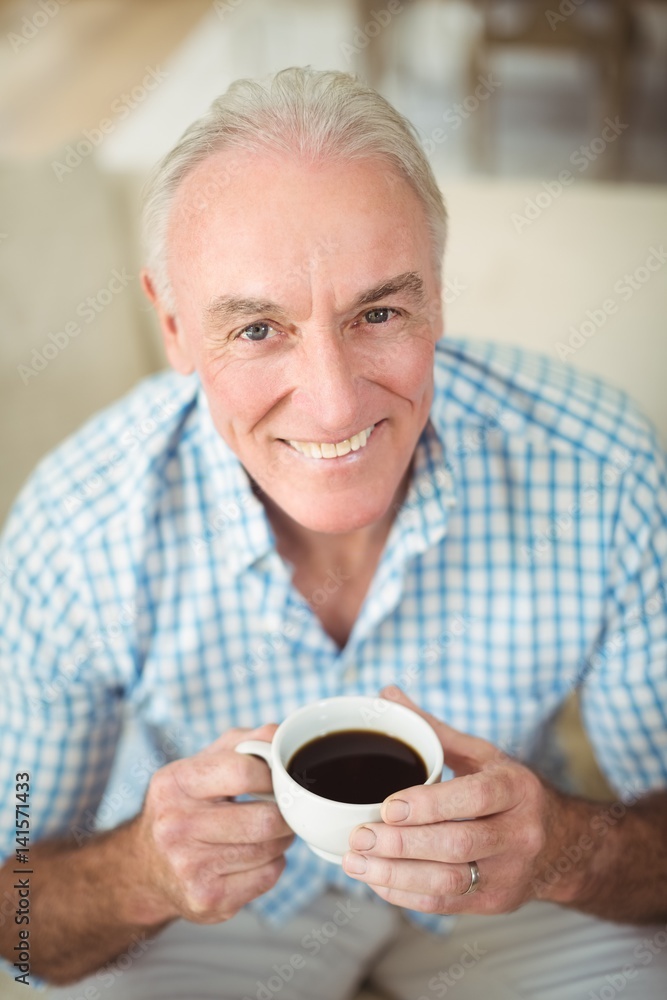 Smiling senior man having cup of coffee in living room Smiling senior man having cup of coffee in living room