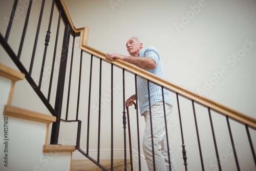 Senior man climbing upstairs with walking stick