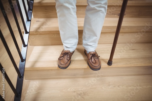 Obraz na plátně Senior man climbing downstairs with walking stick
