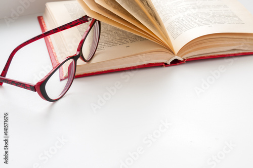 On the open book glasses lie on a light background