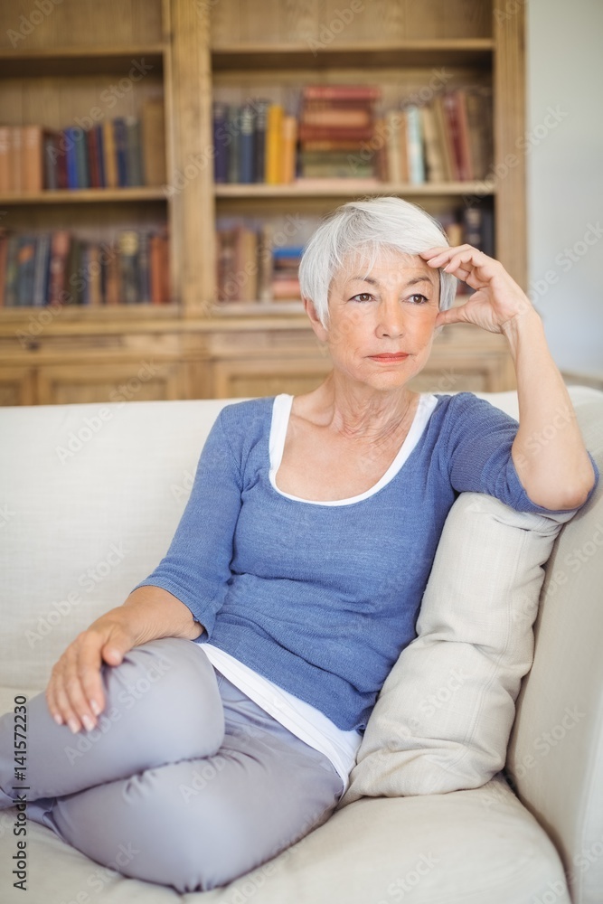Obraz premium Thoughtful senior woman sitting on sofa in living room