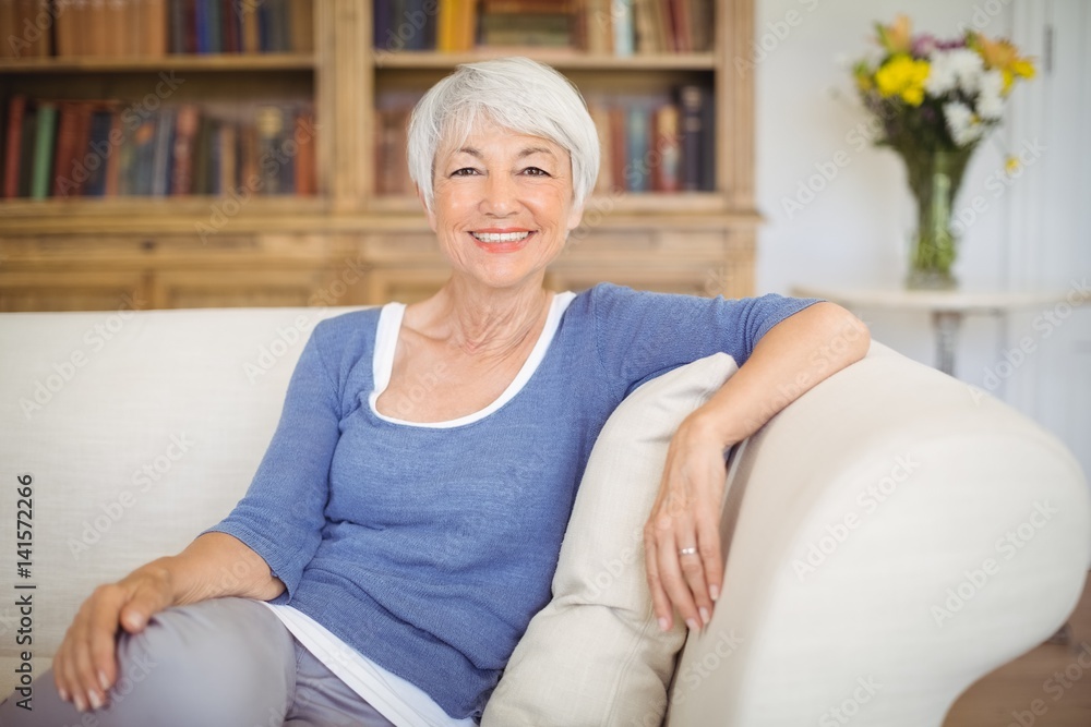 Portrait of smiling senior woman sitting on sofa in living room Portrait of smiling senior woman sitting on sofa in living room