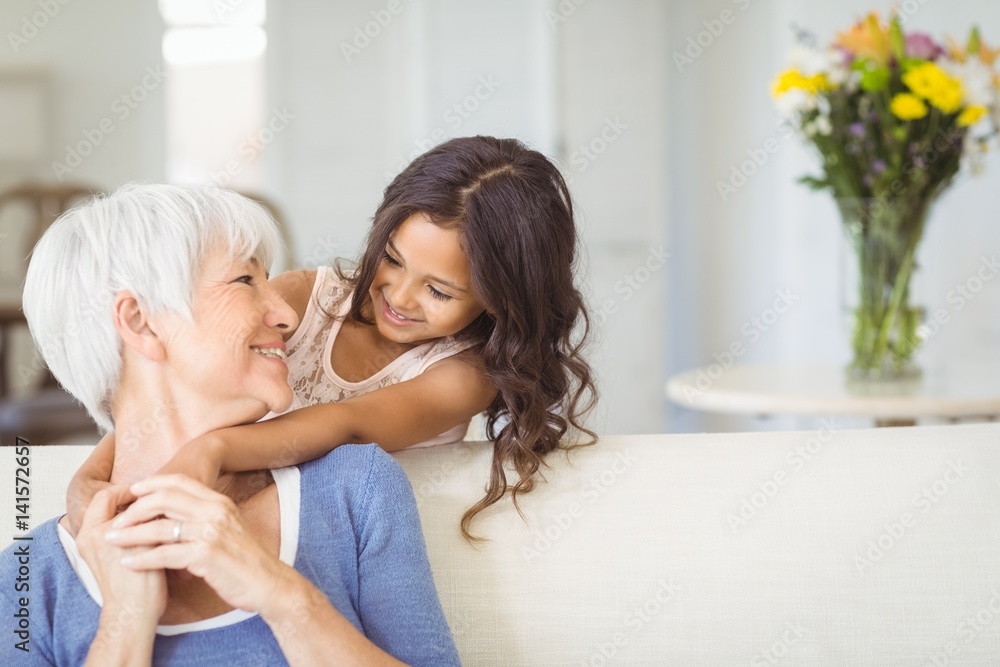 Granddaughter embracing her grandmother in living room Granddaughter embracing her grandmother in living room