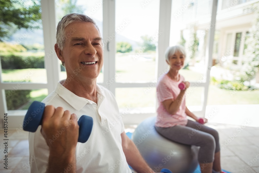 Senior couple exercising with dumbbells on exercise ball Senior couple exercising with dumbbells on exercise ball