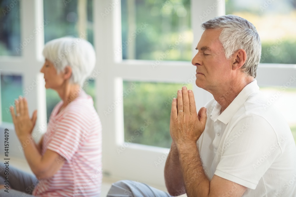 Senior couple performing yoga on exercise mat Senior couple performing yoga on exercise mat