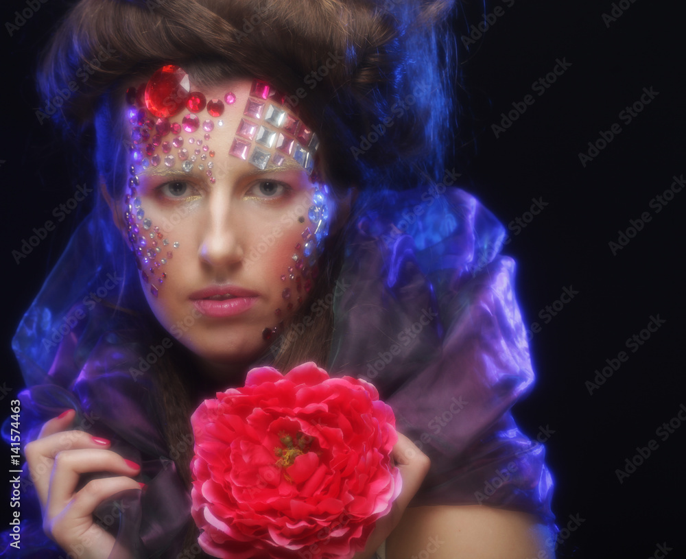 young woman with artistic visage holding big red flower