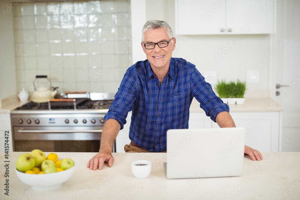 Portrait of senior man with laptop in kitchen Portrait of senior man with laptop in kitchen
