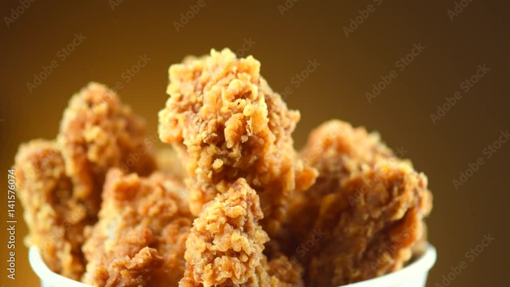 Rotation bucket full of crispy fried chicken on brown background. 4K video footage. Ultra high definition 3840X2160 Rotation bucket full of crispy fried chicken on brown background. 4K video footage. Ultra high definition 3840X2160