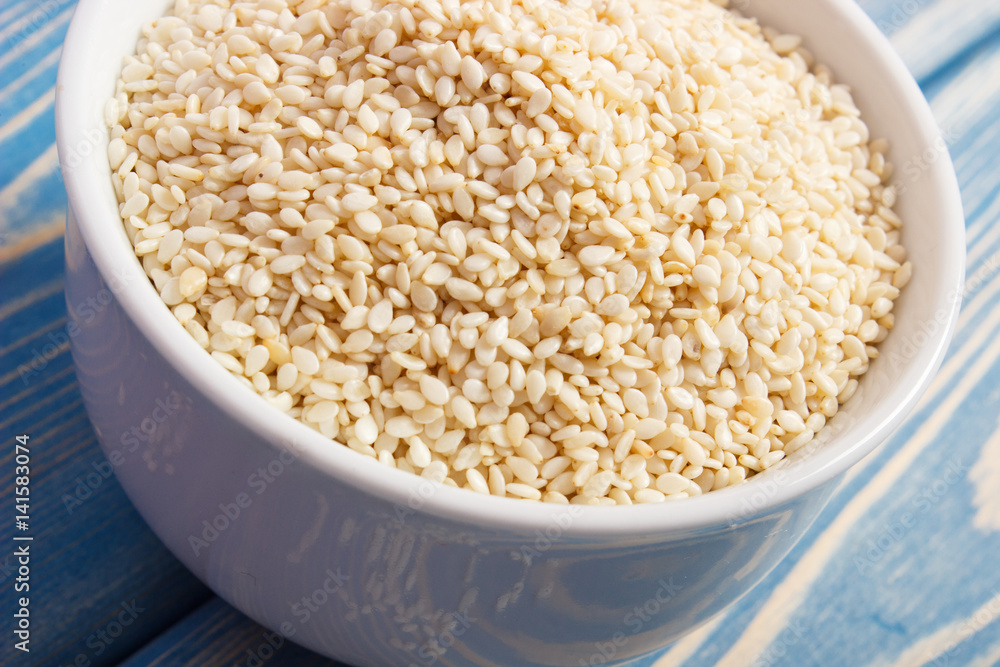 Heap of sesame seeds in white bowl on wooden boards Heap of sesame seeds in white bowl on wooden boards