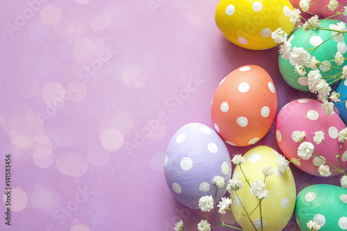 Easter eggs and white flowers on purple background. Space for text.