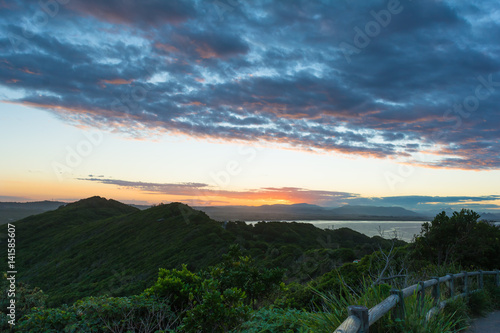 The stunning sunset bright sky and cumulus blue and orange clouds and the view on montains hills and ocean in Byron Bay , Australia