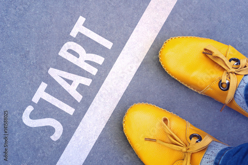 Feet in the yellow shoes standing on start line - business concept photo