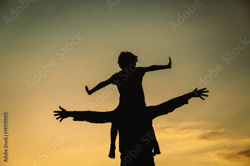 father and son play on sunset sky