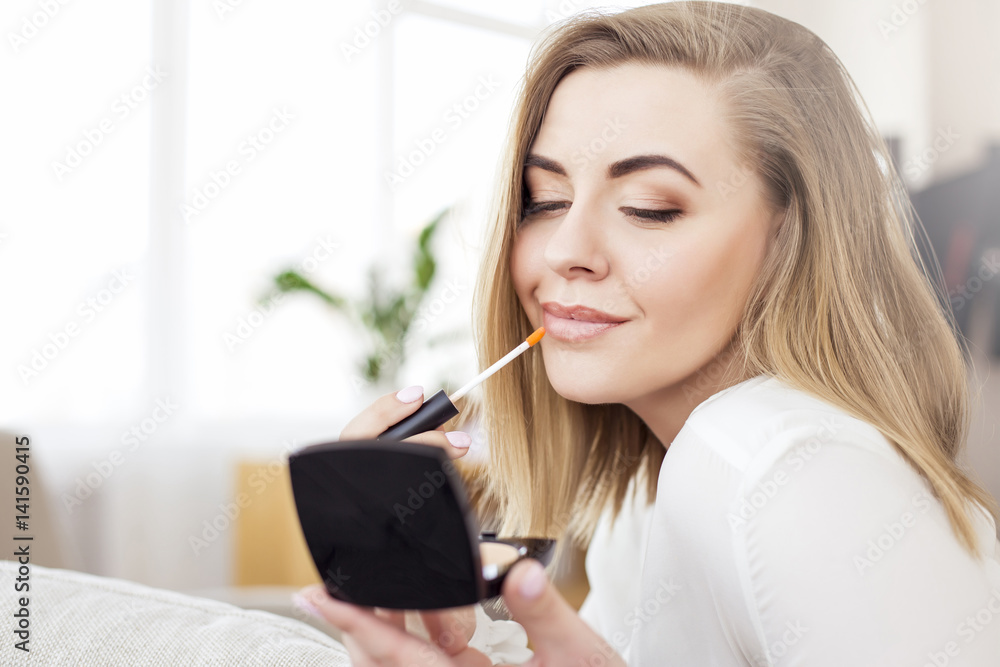 Beautiful young blond hair woman doing make-up and smiling Beautiful young blond hair woman doing make-up and smiling