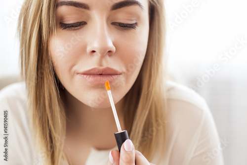 Portrait of happy young woman applying lipstick