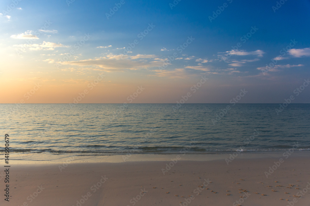 Empty white sandy beach and clear sea at early sunset.