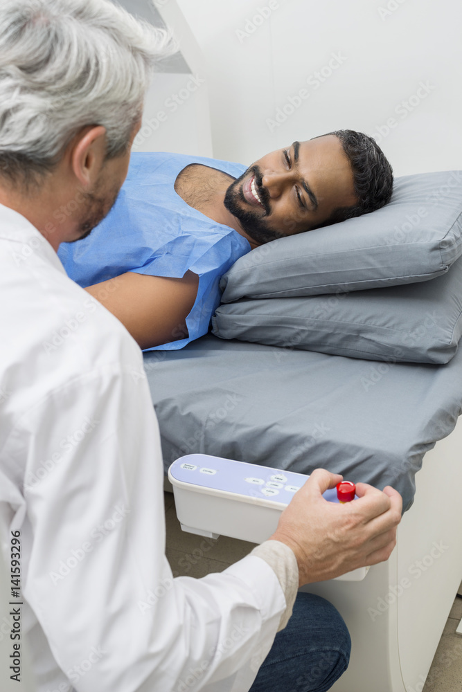 Man Lying On Bed While Looking At Doctor In Hospital Man Lying On Bed While Looking At Doctor In Hospital