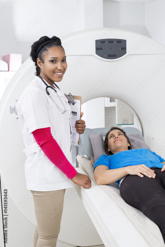 Female Doctor Standing By Patient Undergoing CT Scan