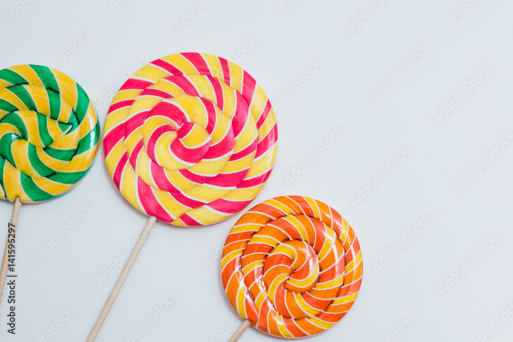 Big yummy lollipops on sticks. Sweet caramel candy on white. Copy space