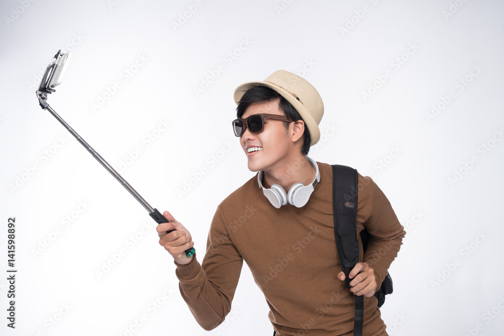 Young tourist asian man taking selfie picture over grey background Young tourist asian man taking selfie picture over grey background
