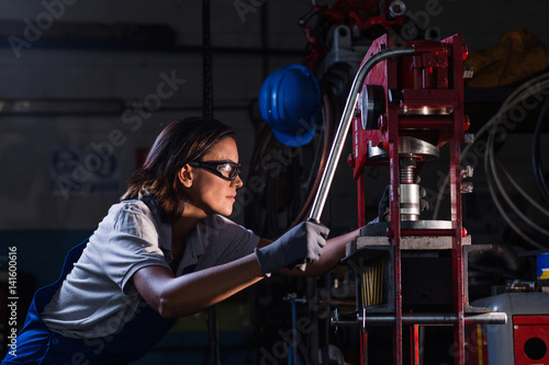 female mechanic operating hydraulic press