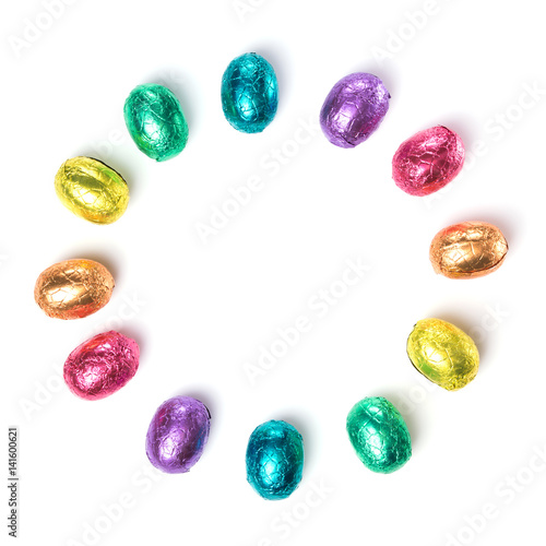 Circle made of chocolate easter eggs wrapped in multi colored foil isolated on white background